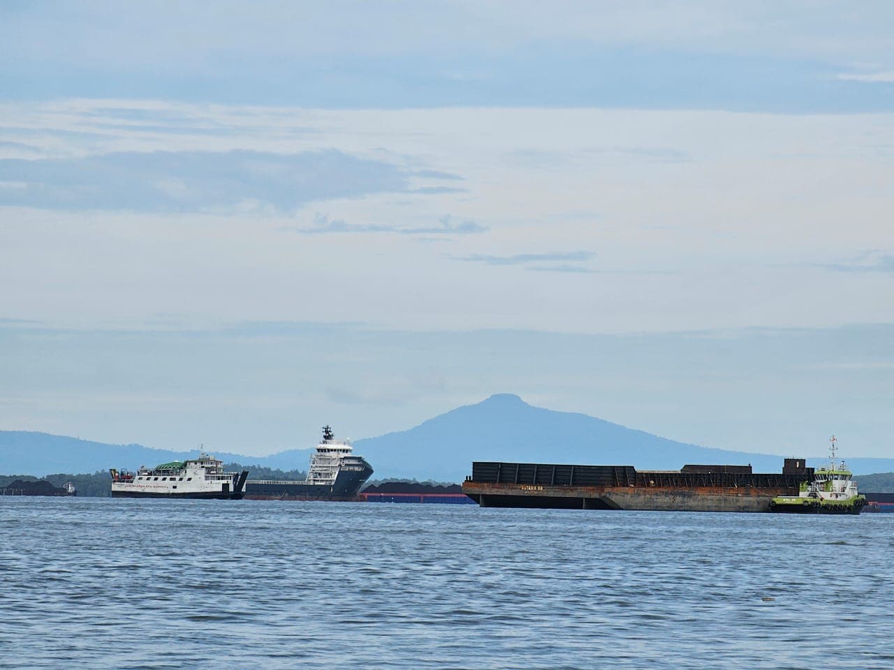 Sebuah ponton melintas di Teluk Balikpapan dengan latar Gunung Lumut Kabupaten Paser. 