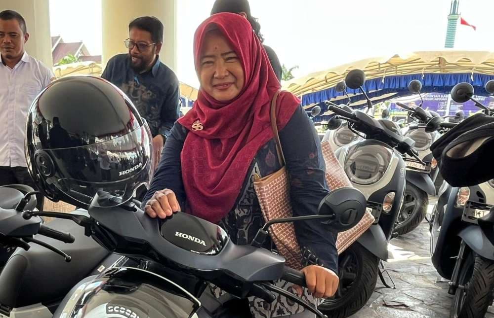 Ketua RT 46, Ade Romaningsih dengan sepeda motor bantuan Pemkab Kutim. (Foto: Prokom Kutim)